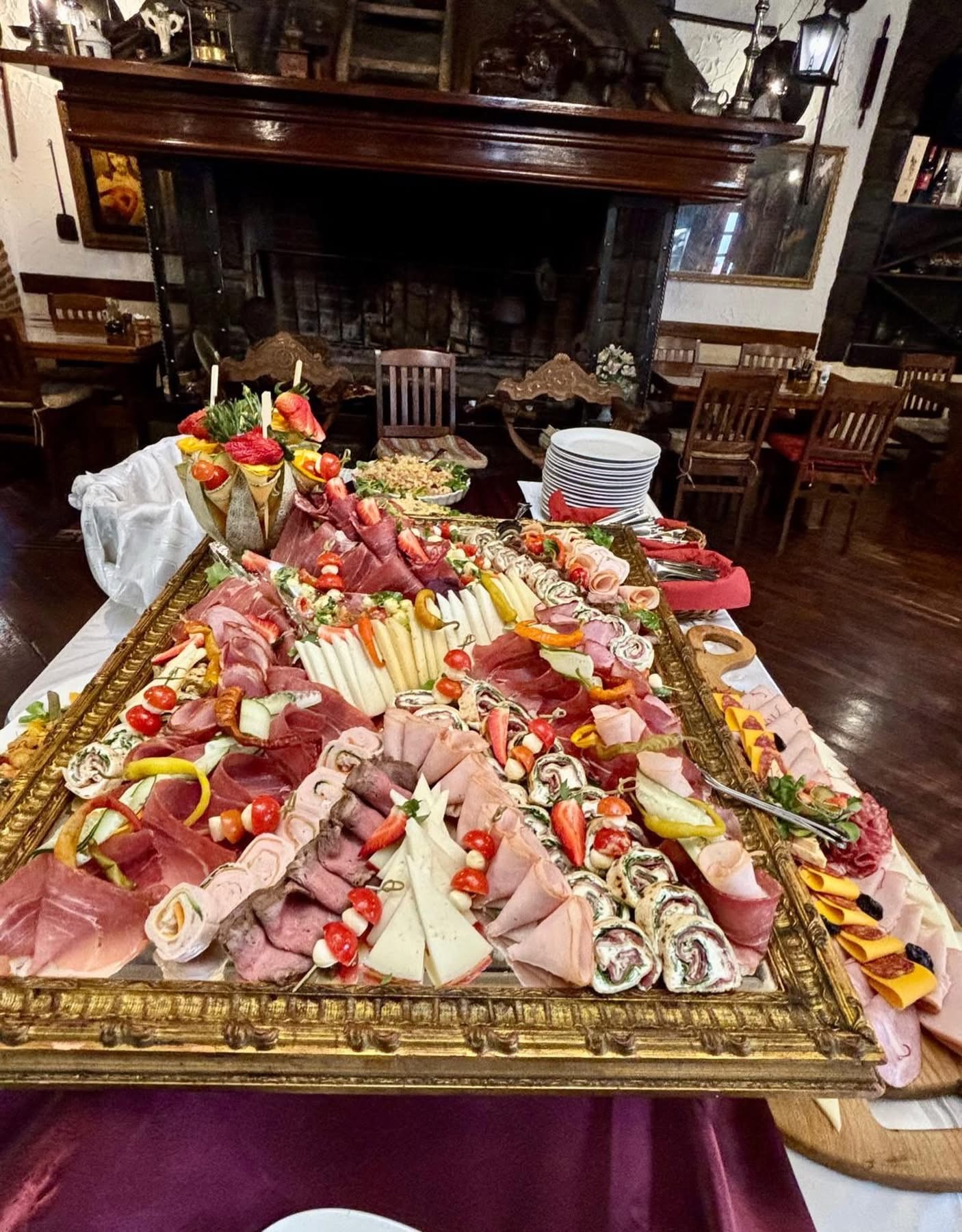 Charcuterie and cheese platter overflowing in front of the fireplace