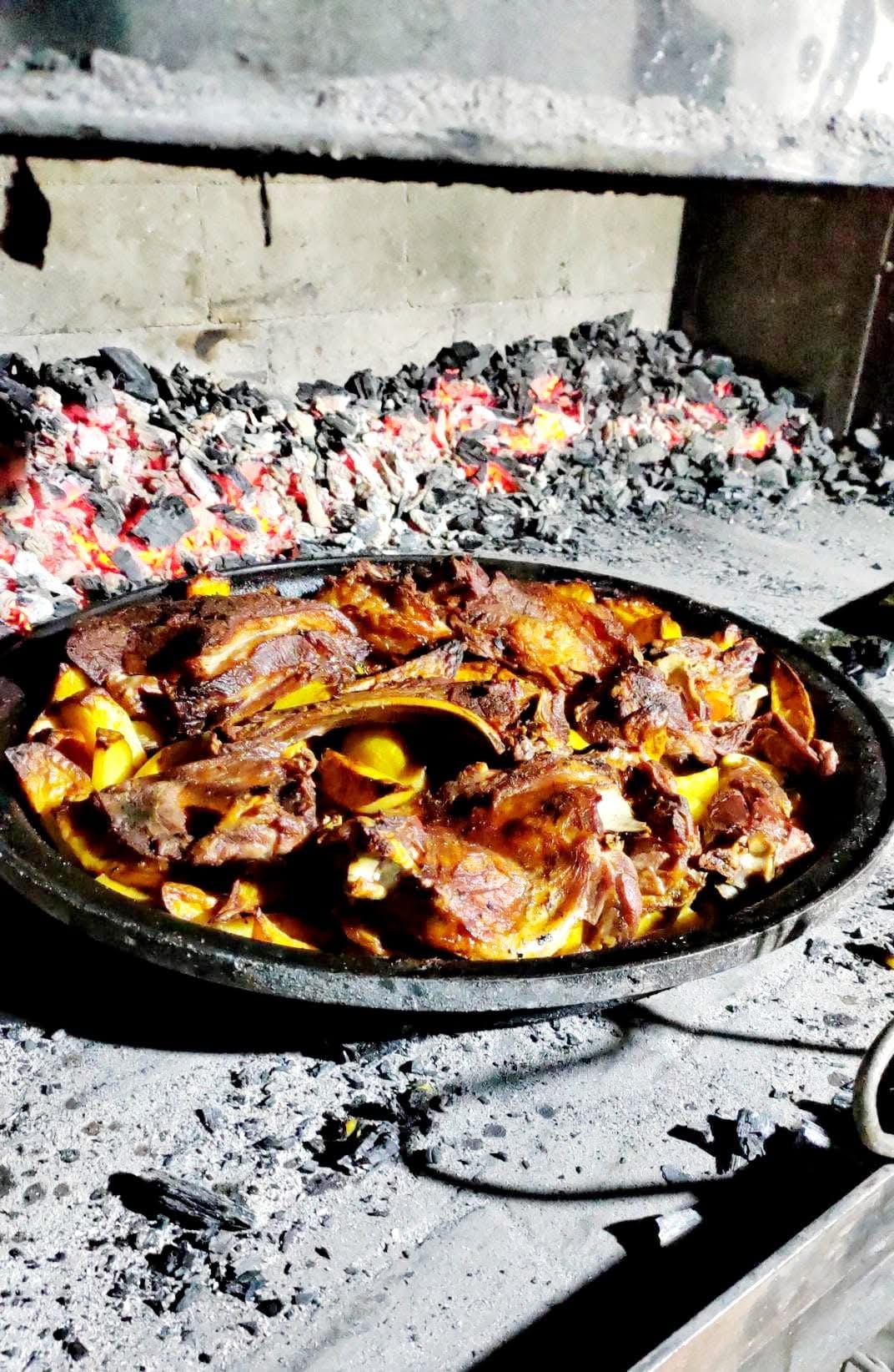 Roasted meat and potatoes over glowing embers