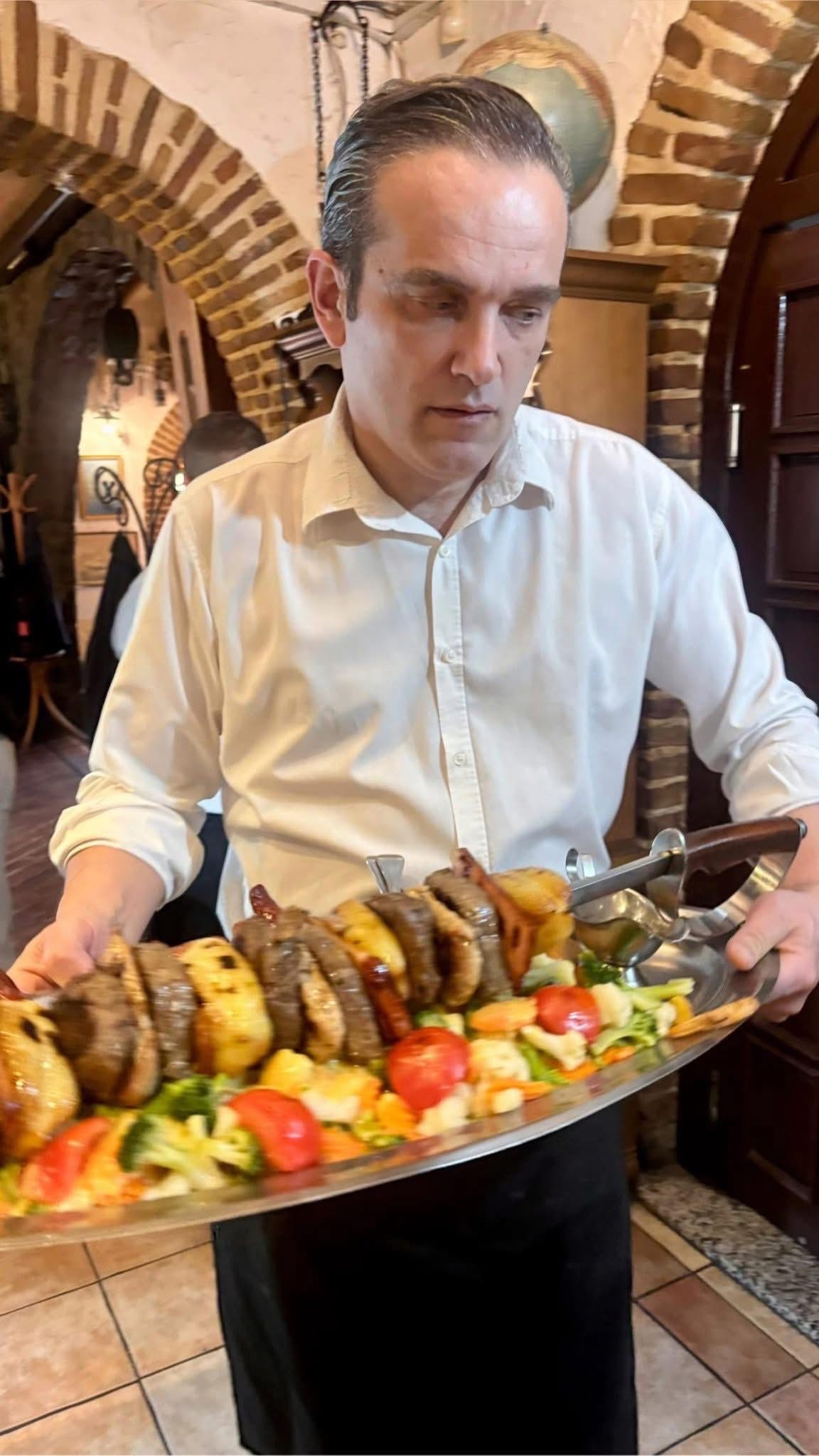 Waiter holding a large meat and potato skewer platter