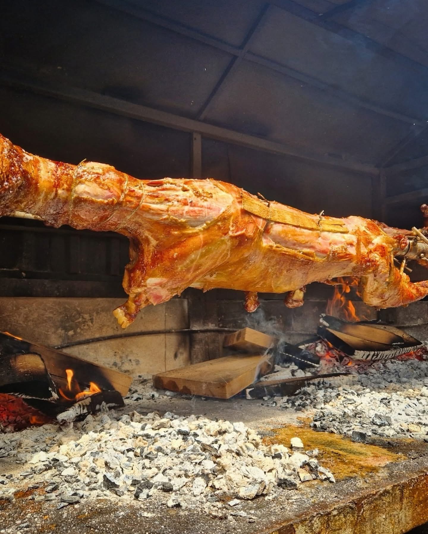 Whole animal roasting on a spit over coals